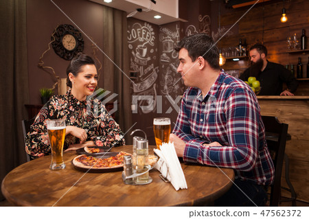 Happy couple drinking beer and eating pizza. Happy couple drinking beer and eating pizza. 47562372