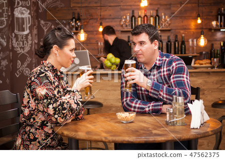 Attractive couple drinking beer in a beautiful hipster pub. 47562375