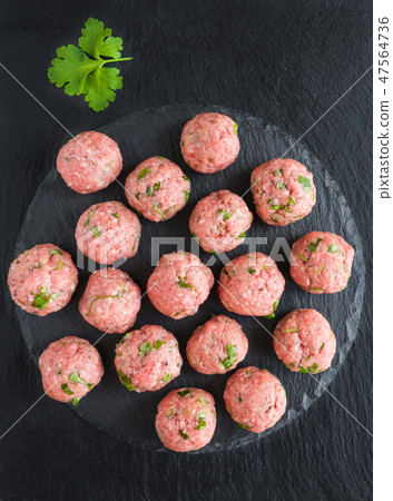 Uncooked raw meatballs on black cutting board 47564736