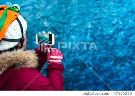 Woman taking photo in blue ice cave in Iceland 47565230