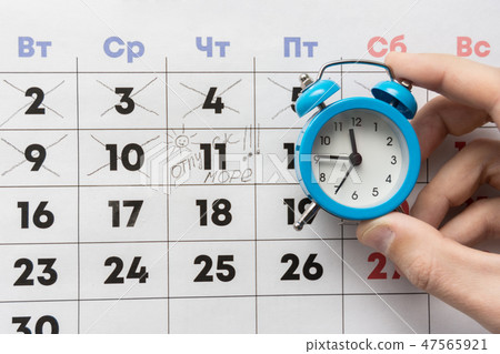 A hand holds a small alarm clock, A hand holds a small alarm clock, 47565921