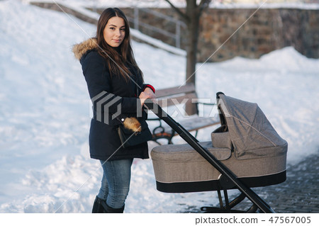 Young mother walking with her baby in pram. Beautiful stoller. Winter photosession Young mother walking with her baby in pram. Beautiful stoller. Winter photosession 47567005