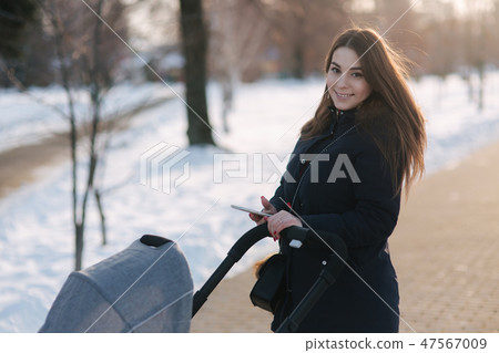 Mom walk with baby in pram. Winter park. Happy woman with her baby 47567009