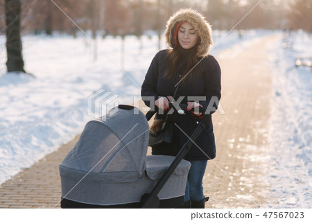 Mom walk with baby in pram. Winter park. Happy woman with her baby Mom walk with baby in pram. Winter park. Happy woman with her baby 47567023