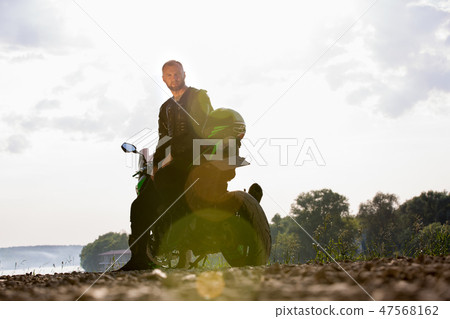 Biker man and motorcycle with river background, Rider moto trip on the street at the riverside 47568162
