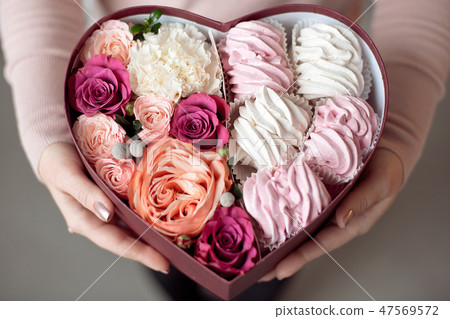 Bouquet of flowers and marshmallows in a gift box of heart in female hands.Congratulatory concept Bouquet of flowers and marshmallows in a gift box of heart in female hands.Congratulatory concept 47569572