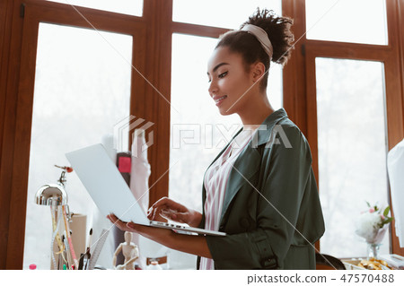 Online orders by email. Young woman tailor with laptop is answering emails Online orders by email. Young woman tailor with laptop is answering emails 47570488