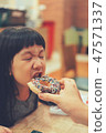 little kid girl eating donut in shop. child having funny with donut 47571337