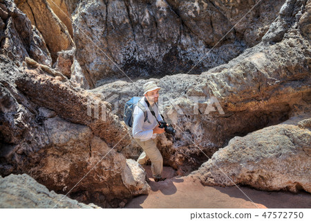 smiling backpacker goes down path between rocks smiling backpacker goes down path between rocks 47572750