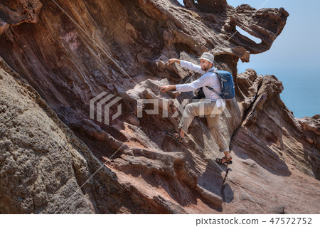 Tourist climbs on a rock to take pictures. 47572752