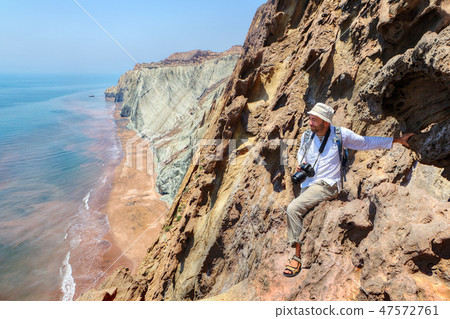 Pleased nature photographer sits on edge of cliff Pleased nature photographer sits on edge of cliff 47572761