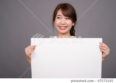 Asian woman showing empty white board with copyspace 47573285