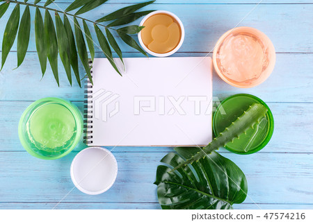 gel of snail, eye patch and Aloe Vera Gel in jar with paper notebook on blue wooden background. Copy gel of snail, eye patch and Aloe Vera Gel in jar with paper notebook on blue wooden background. Copy 47574216