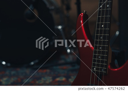 Red bass guitar on a home musical studio. Red bass guitar on a home musical studio. 47574262
