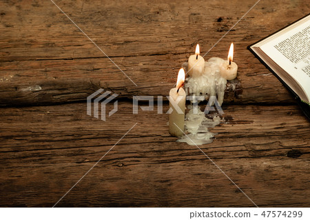 Bible and candle on a old oak wooden table.  47574299