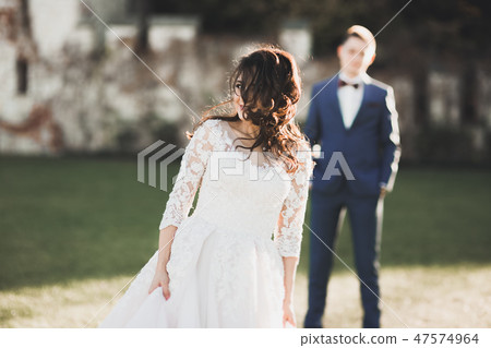 Romantic, fairytale, happy newlywed couple hugging and kissing in a park, trees in background Romantic, fairytale, happy newlywed couple hugging and kissing in a park, trees in background 47574964