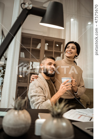 Attractive dark-haired woman with wide smile chilling on knees of her man 47575670