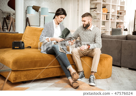 Resolute dark-haired woman observing pieces of material 47576024