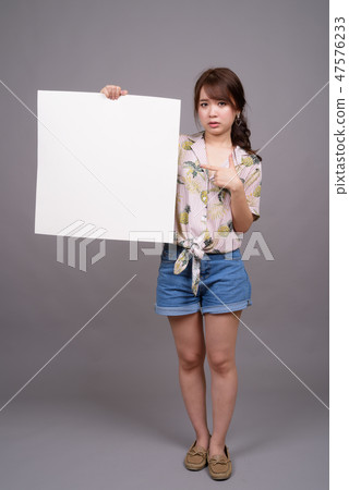 Asian woman holding empty white board with copyspace Asian woman holding empty white board with copyspace 47576233