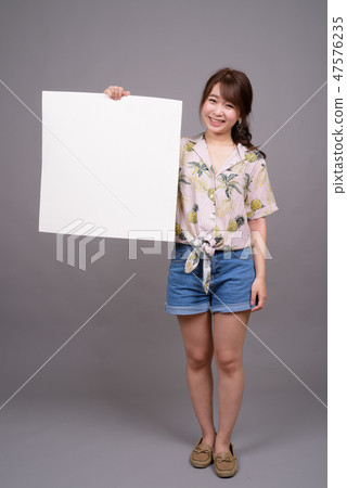 Asian woman holding empty white board with copyspace Asian woman holding empty white board with copyspace 47576235