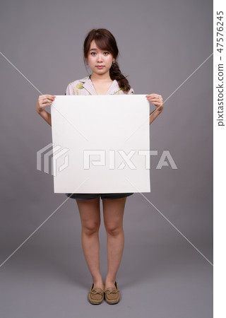 Asian woman holding empty white board with copyspace 47576245