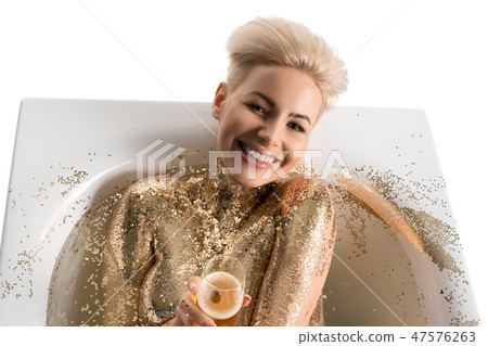 Cheerful blonde in golden glitters lying in bath 47576263