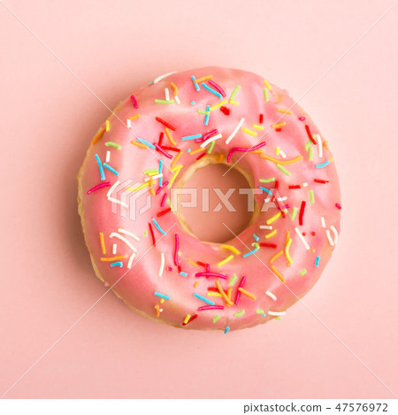 Donut decorated with sprinkles on coral background. Living coral color. Flat lay. Top view Donut decorated with sprinkles on coral background. Living coral color. Flat lay. Top view 47576972