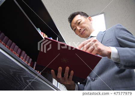 Middle-aged businessman reading books Middle-aged businessman reading books 47577979