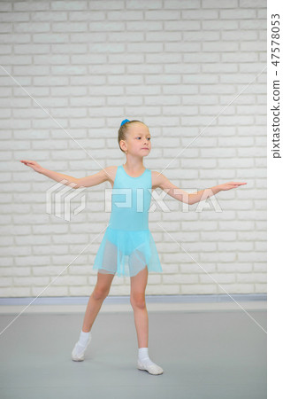Little ballerina in blue dress and pointe shoes is dancing in ballet school. Cute girl in dance 47578053