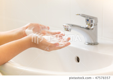 Children washing hand with foamnsoap in bathroom sink. 47578357