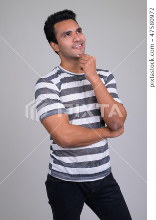 Portrait of happy young handsome Indian man thinking 47580972