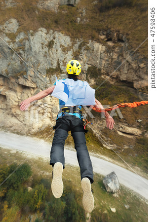 A man in a helmet jumps ropeup with an empty flag in the mountains. Extreme sports. Leisure. Top A man in a helmet jumps ropeup with an empty flag in the mountains. Extreme sports. Leisure. Top 47598406