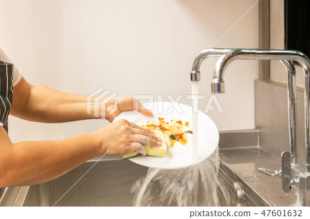Hands washing dirty dishes with running water 47601632