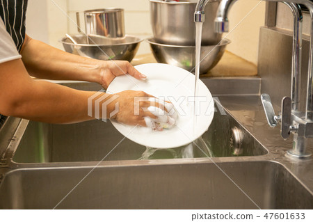 Hands washing dirty dishes with running water 47601633