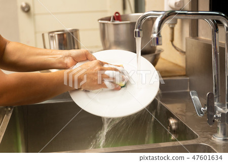 Hands washing dirty dishes with running water 47601634