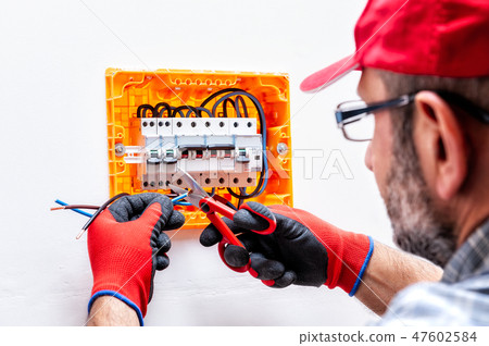 Electrician at work on an electrical panel. 47602584