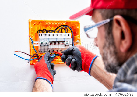 Electrician at work on an electrical panel. Electrician at work on an electrical panel. 47602585
