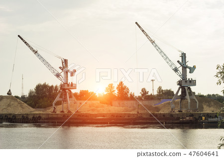 Two port cranes at the riverbank produce river sand, sunset, barge Two port cranes at the riverbank produce river sand, sunset, barge 47604641