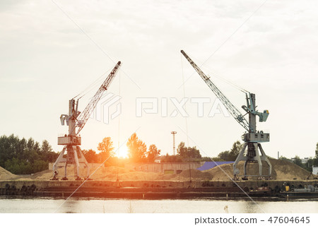 Two port cranes at the riverbank produce river sand, sunset, barge Two port cranes at the riverbank produce river sand, sunset, barge 47604645