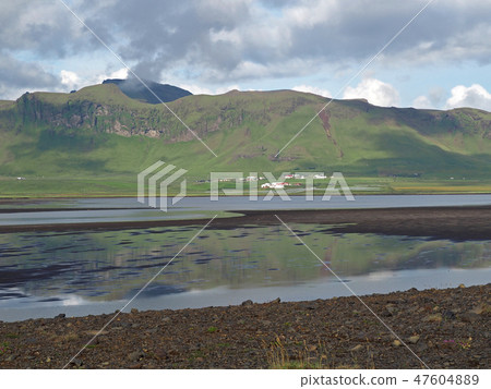 iceland green hills near Vik village with shallow water lake and dark clouds reflected on water iceland green hills near Vik village with shallow water lake and dark clouds reflected on water 47604889