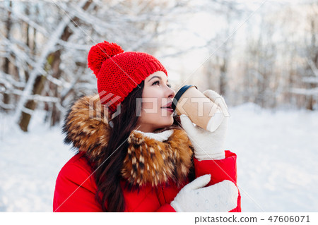 Portrait of young beautiful woman in winter park . Drinking coffee and enjoying life. 47606071