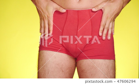 a man in red boxers dancing on a yellow background. close-up. 47606294