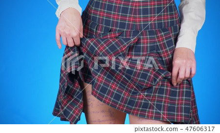 Midsection of teenage girl, cheat sheet written on hips hidden under a skirt. close-up, blue Midsection of teenage girl, cheat sheet written on hips hidden under a skirt. close-up, blue 47606317