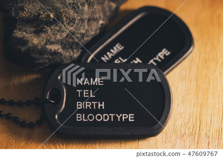Soldier tag or dog tag laid on brown wooden table. 47609767