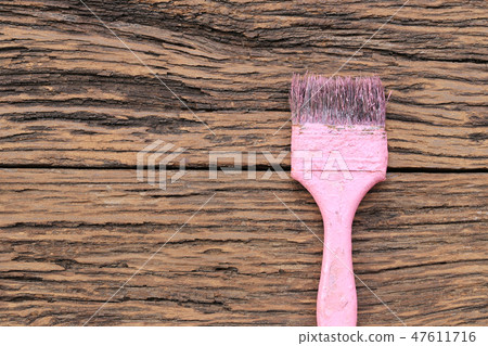 Old pink paint brush on brown wooden floor. 47611716