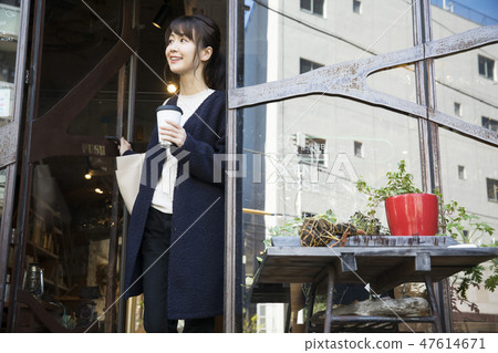 一個拿出咖啡離開商店的女人 47614671