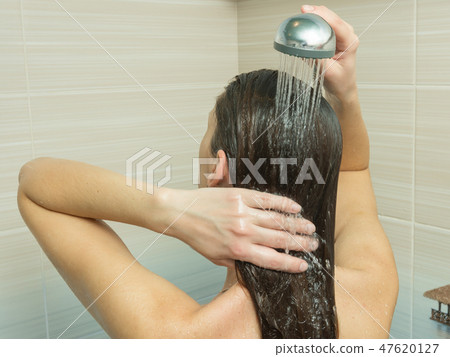 The girl washes her hair in the bathroom under the shower 47620127