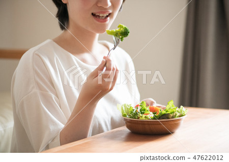 吃西蘭花的一名年輕日本婦女 吃西蘭花的一名年輕日本婦女 47622012