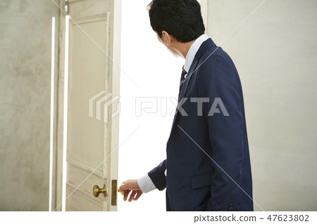 A businessman opening a door 47623802