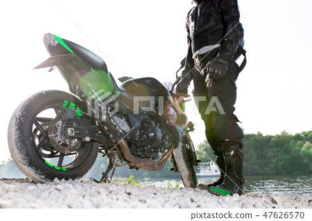 Biker man and motorcycle with river background, Rider moto trip on the street at the riverside Biker man and motorcycle with river background, Rider moto trip on the street at the riverside 47626570